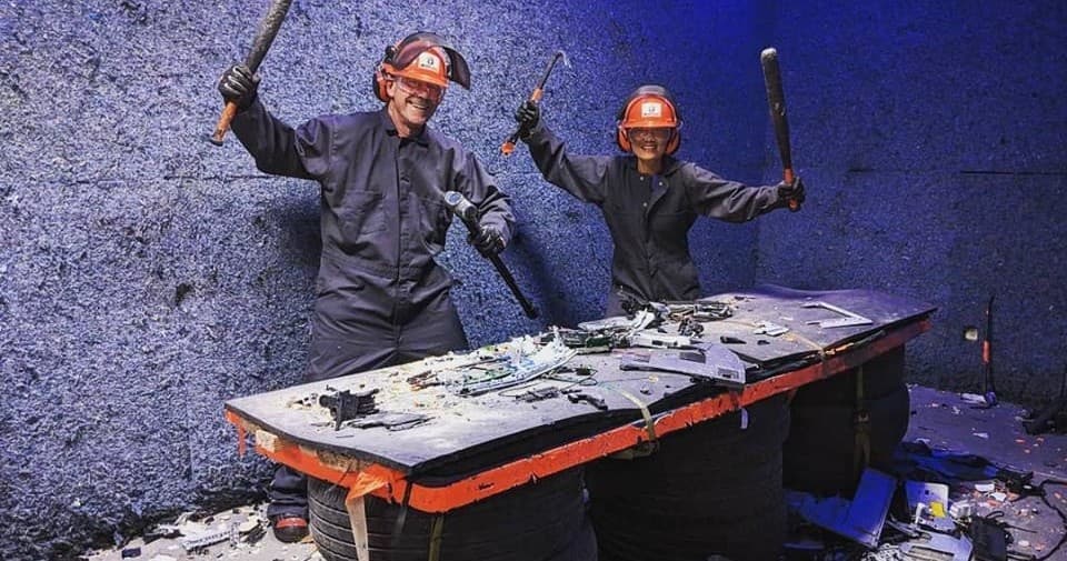 Two participants smashing a table in indoor rage room session