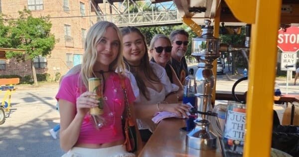 Daytime pedal-party riders enjoying drinks on city street tour