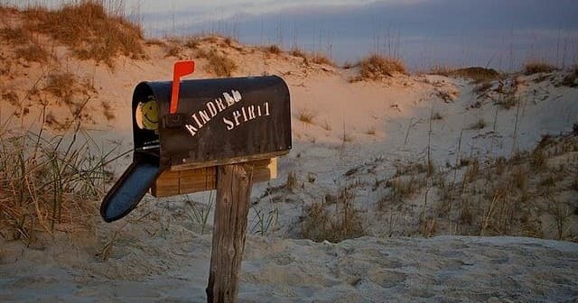 Beachfront mailbox on sandy dunes at coastal sunrise