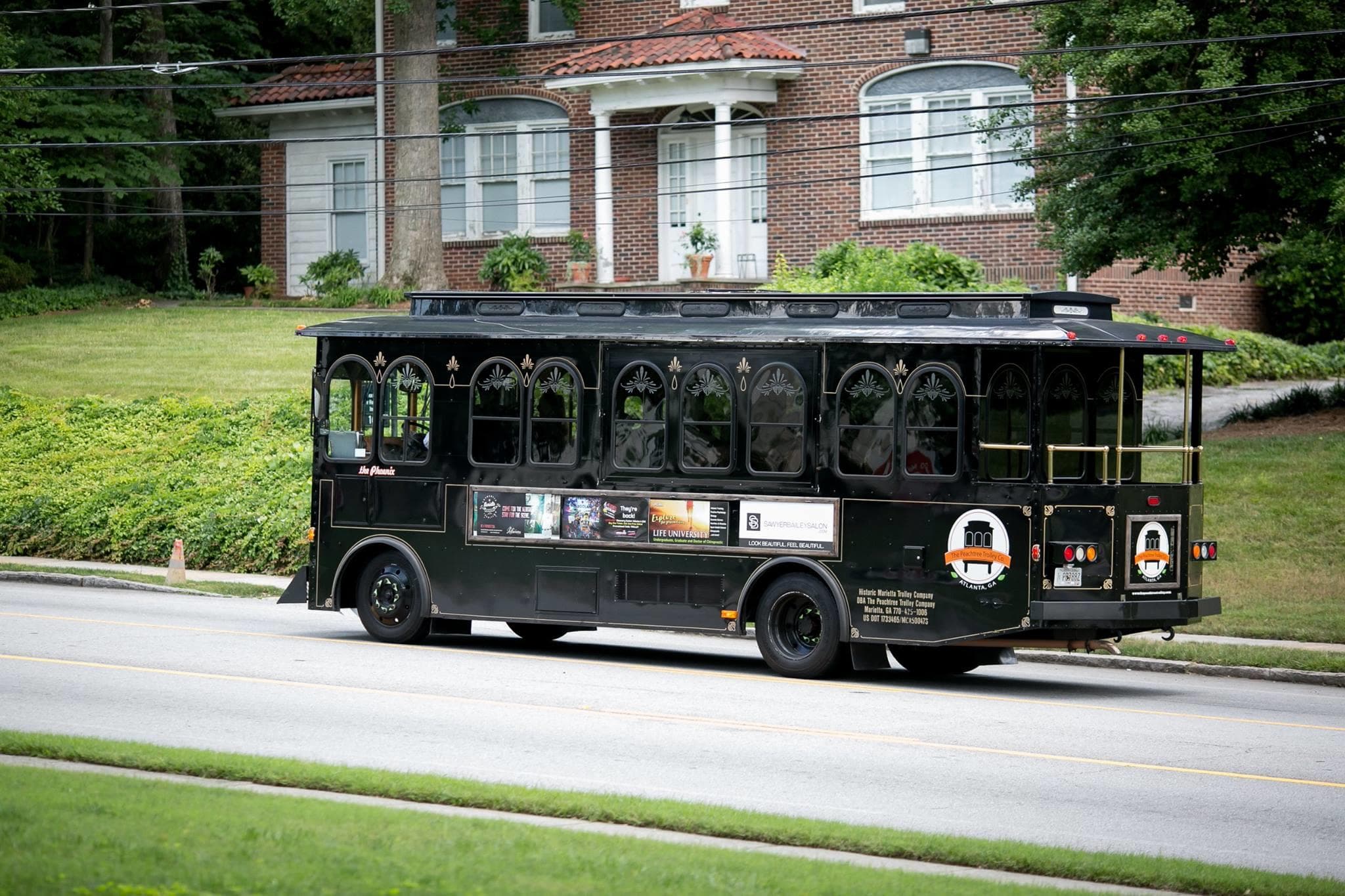 Black vintage trolley passing suburban green lawn on guided tour