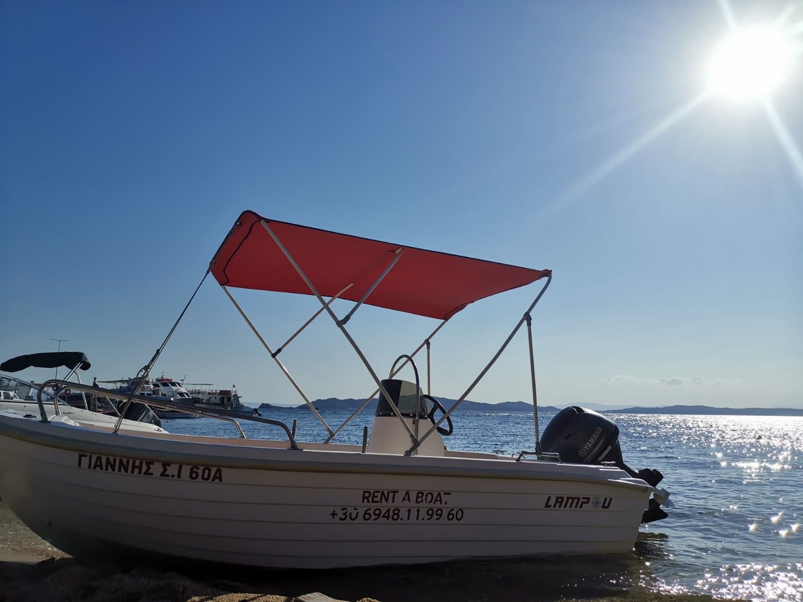 Small boat with red canopy at sea, sunset coastal cruise