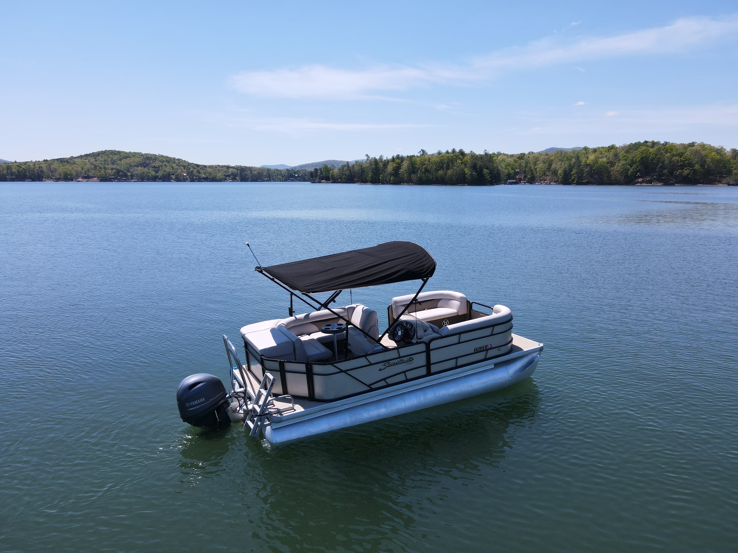 Aerial view of pontoon on clear lake with scenic horizon