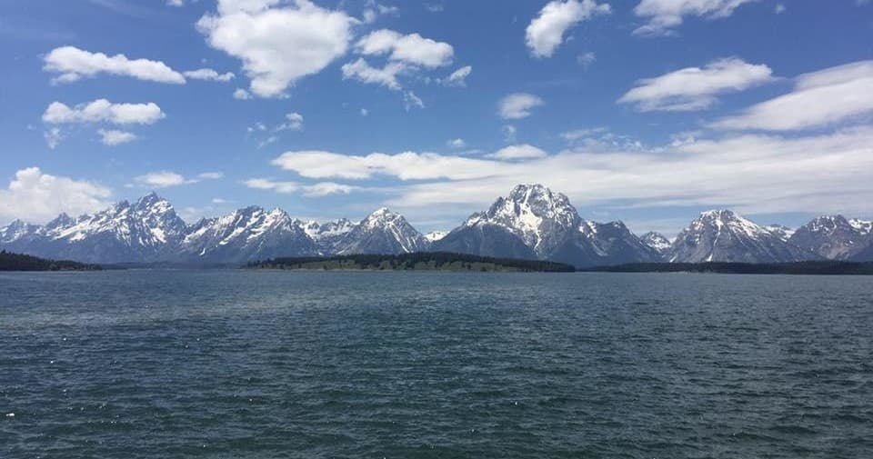 Mountain range beyond alpine lake under blue sky panorama