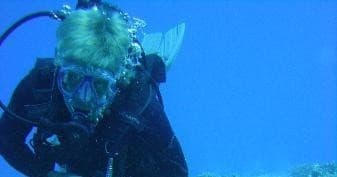 Scuba diver exploring clear blue ocean reef on guided dive