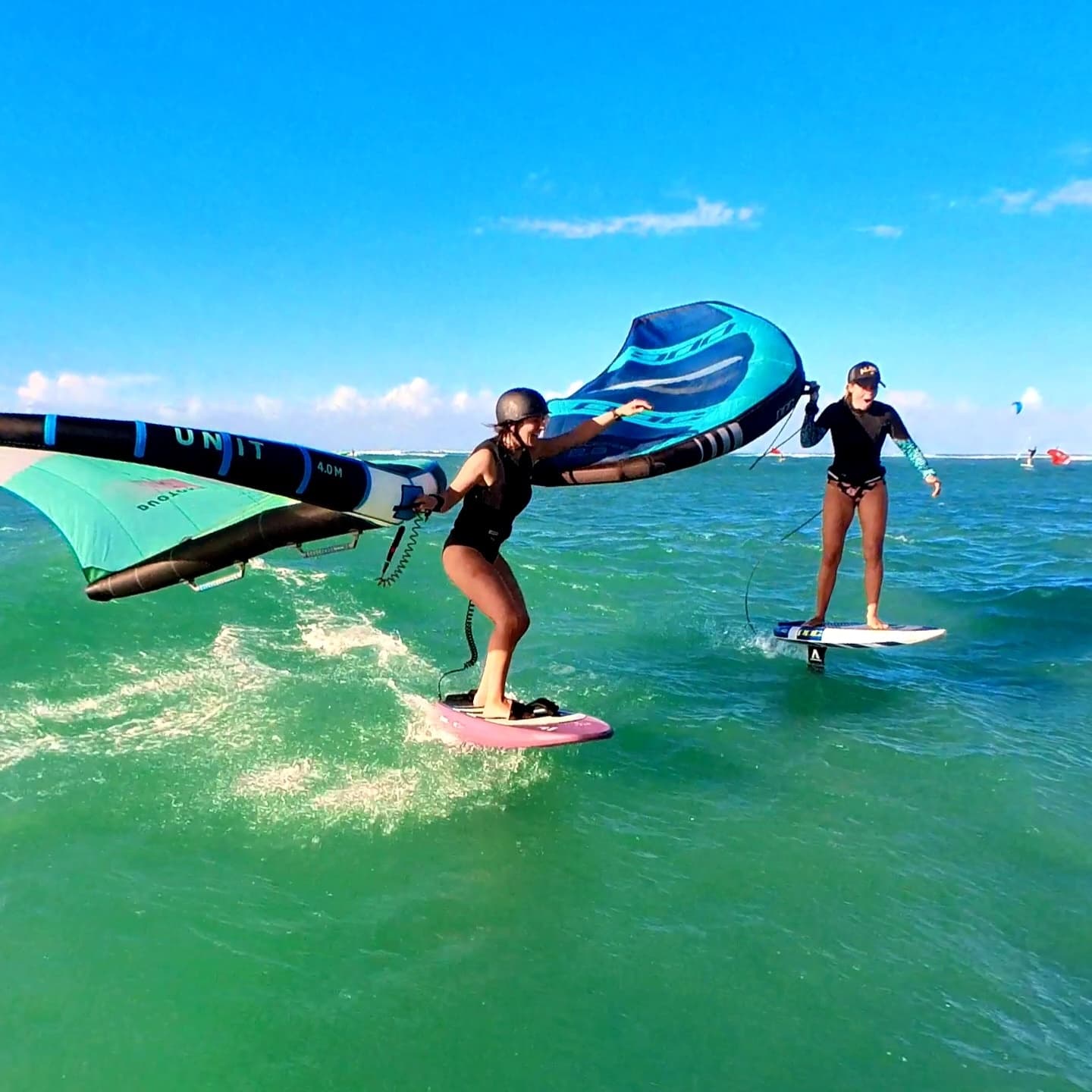 Two riders wing foiling on turquoise Maui ocean, instructional