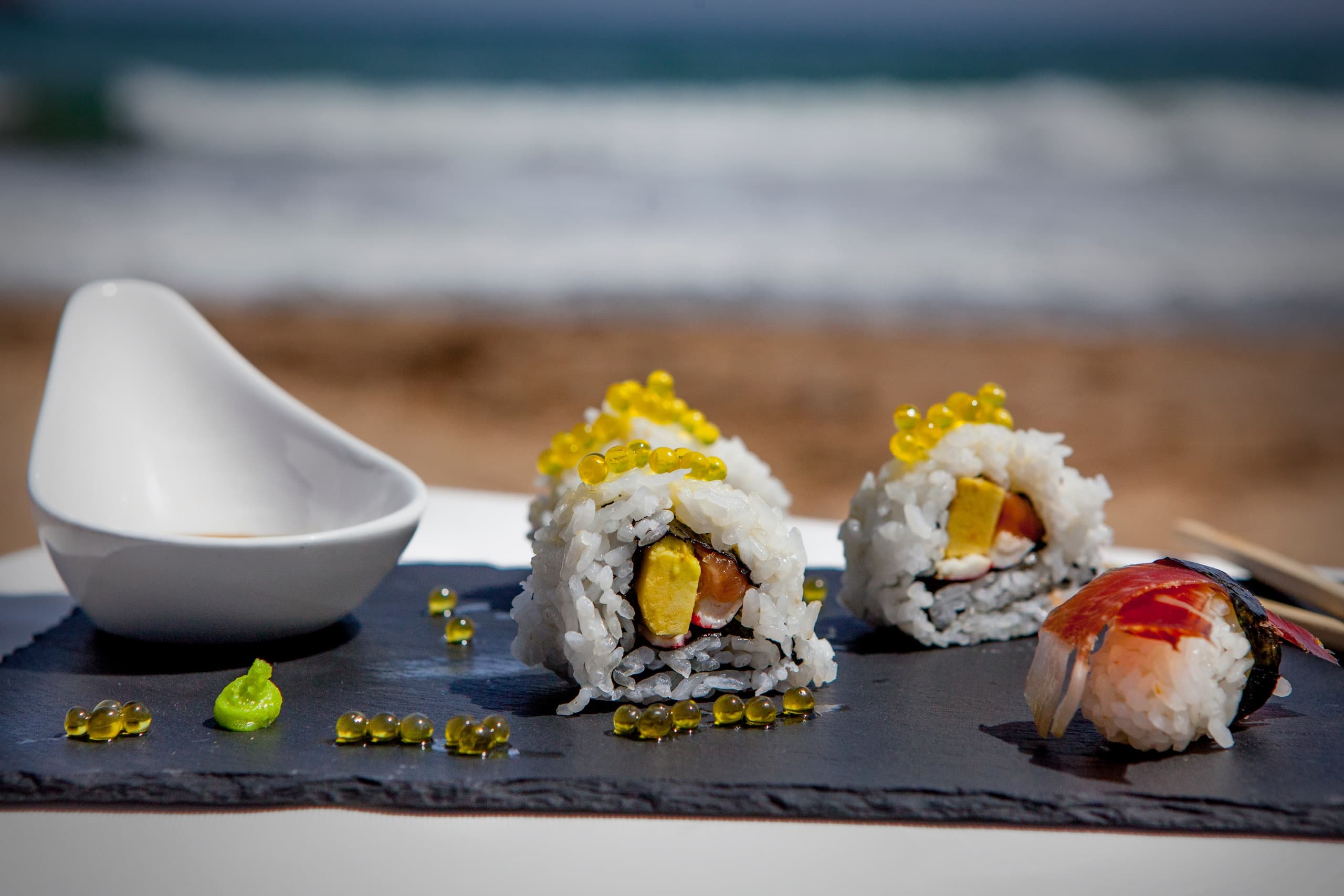 Sushi platter served seaside on slate, beach dining experience