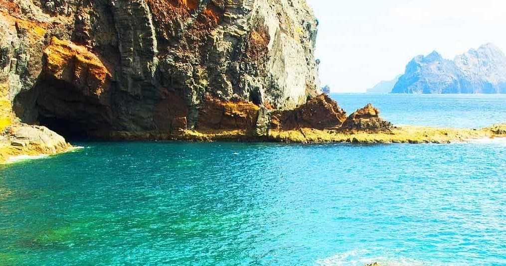 Turquoise coastal cove with anchored sailboats by cliffs