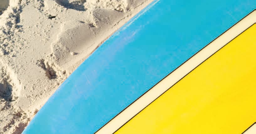 Stacked surfboards on sunlit sandy shore, vibrant beach gear