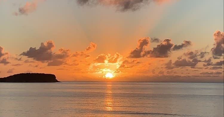 Sunset over calm ocean horizon, coastal seaside viewing
