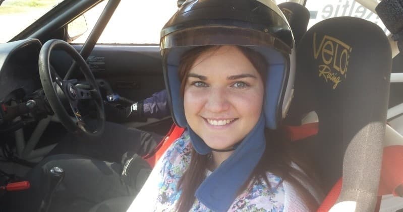 Co-driver wearing helmet smiling inside rally car cockpit pre-stage