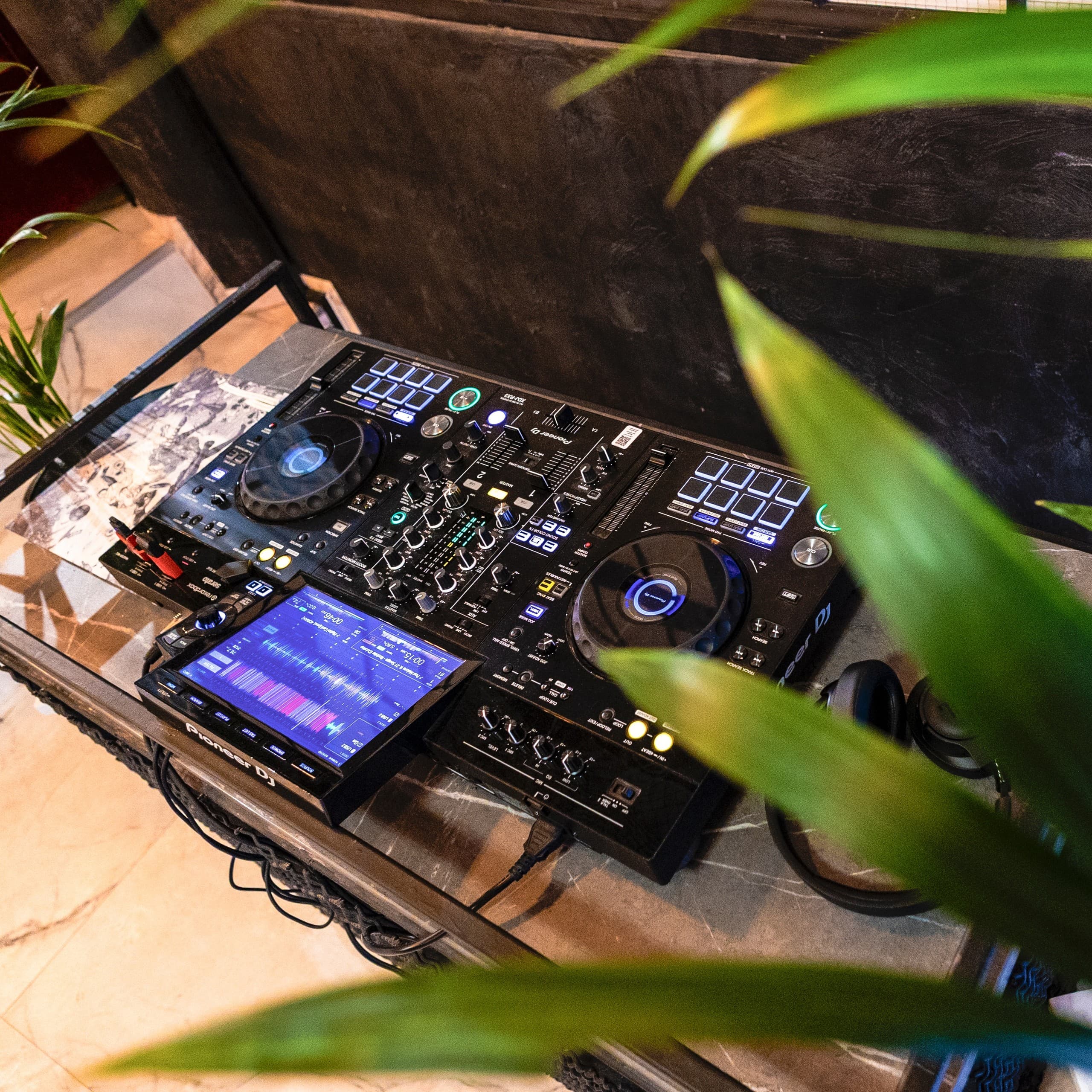 DJ controller station set beside plants in cafe event space