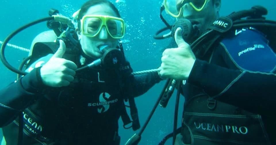 Two scuba divers giving thumbs-up underwater on reef dive