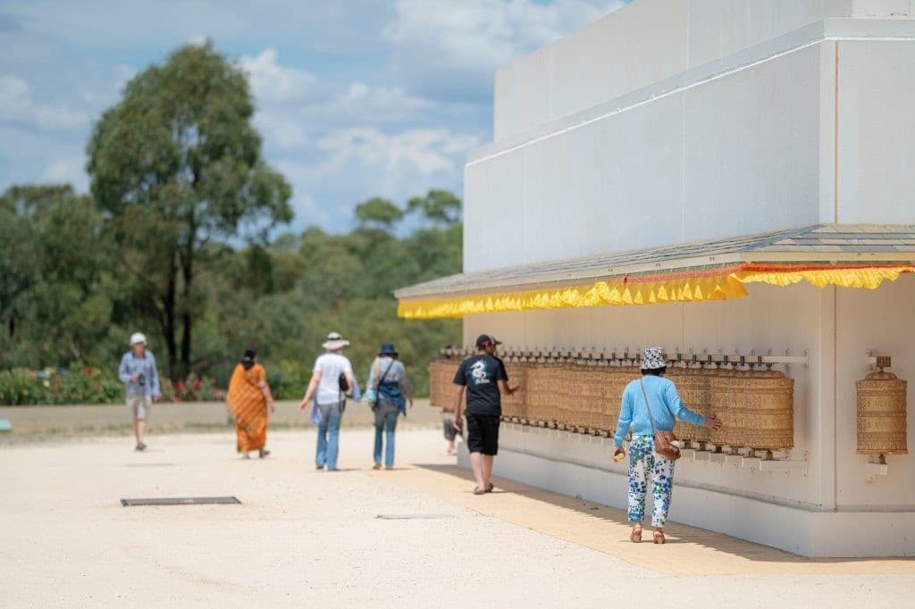 Visitors walking and spinning prayer wheels around stupa base