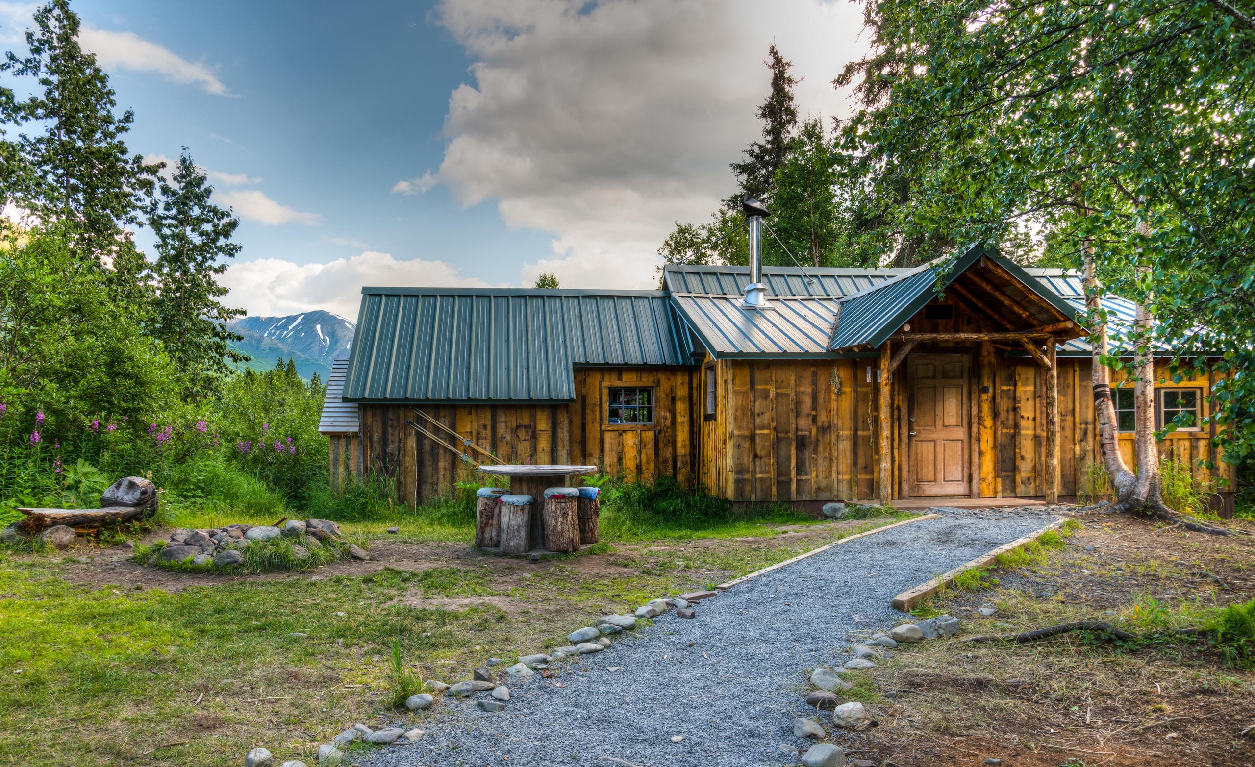 Wooden mountain cabin and trail under cloudy Alaskan sky