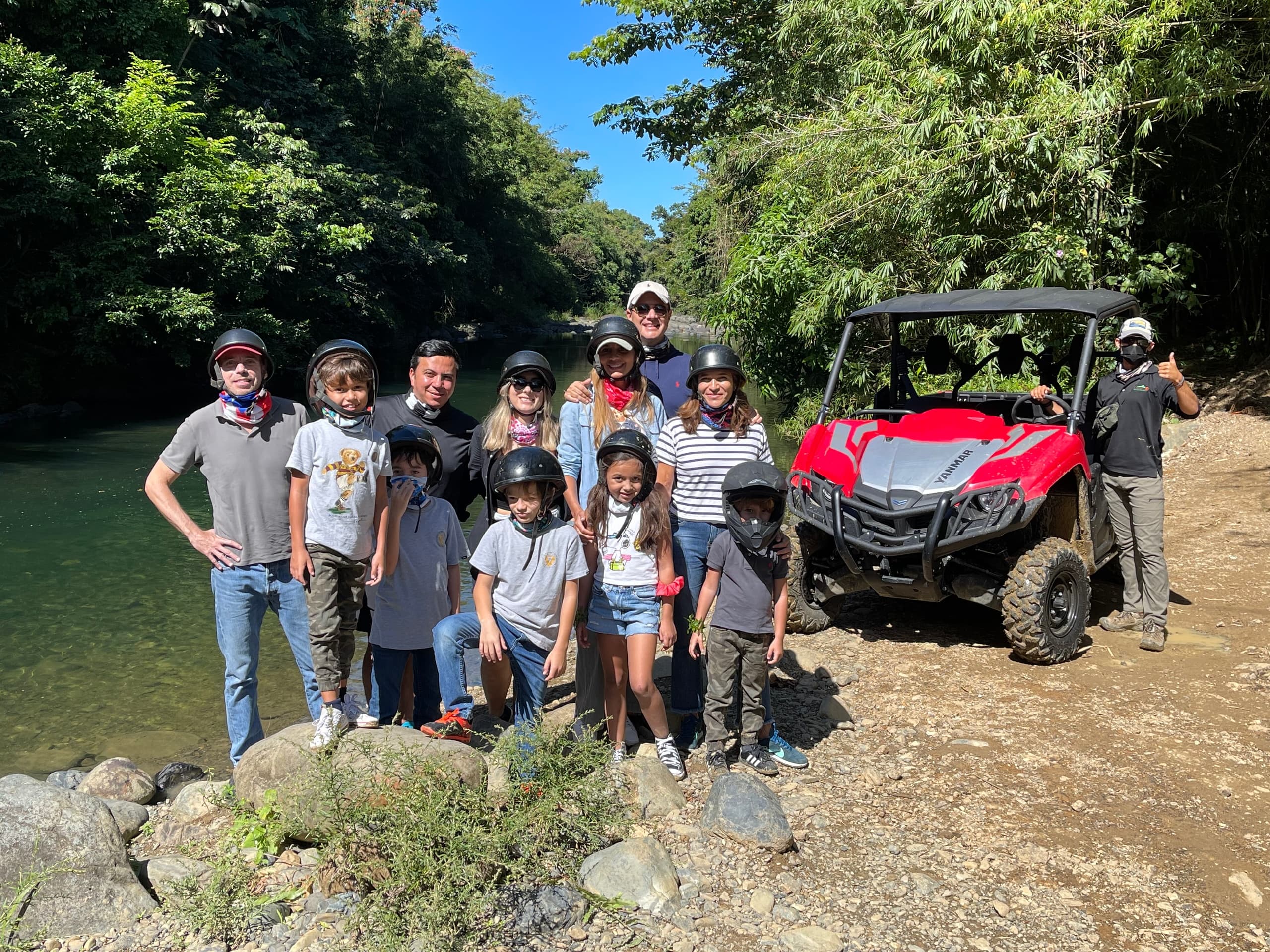 Off-road UTV group posing by river in tropical forest adventure