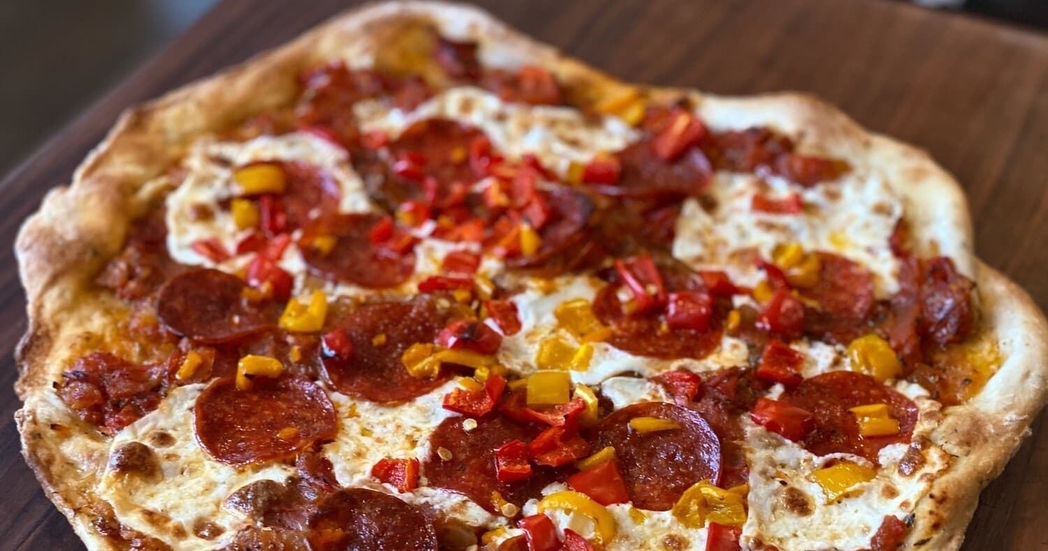 Wood-fired pepperoni pizza on rustic table, casual dining scene