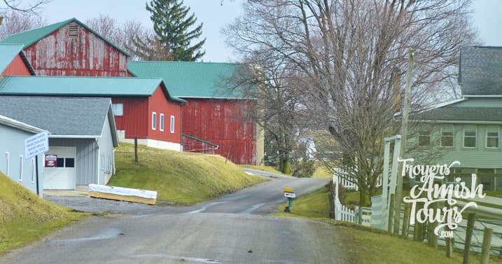 Amish farmland road with red barns and rolling hills, scenic drive