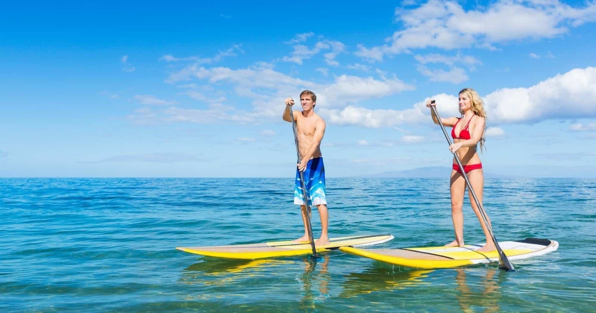Two stand-up paddleboarders on clear tropical ocean near shore