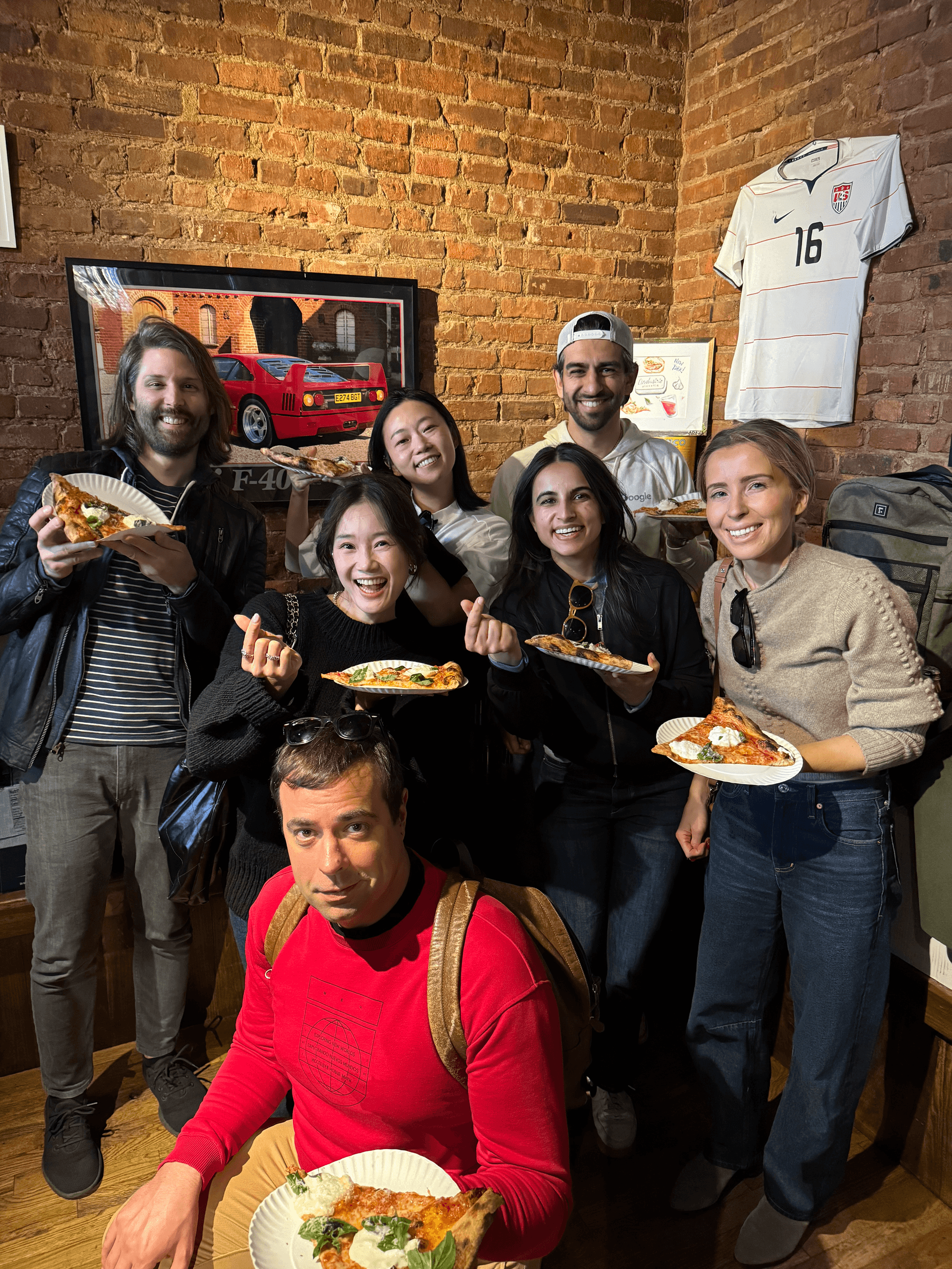 Group enjoying pizza on indoor brick-walled food tour in city