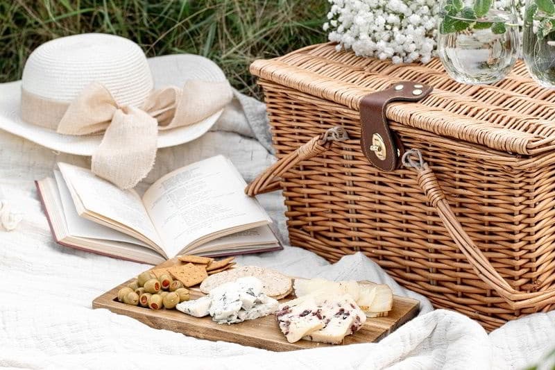 Romantic countryside picnic with wicker basket and cheese