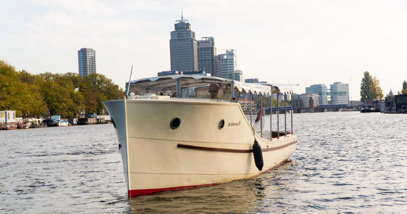 Private sightseeing boat cruising Amsterdam IJ river skyline
