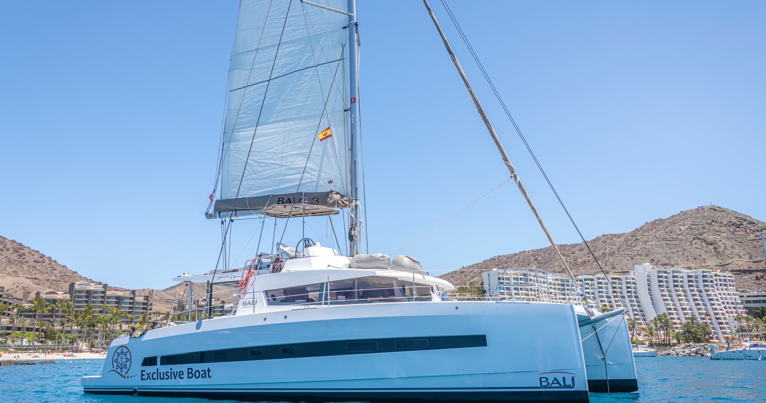 Blue catamaran sailing off coastal resort, calm sea cruise