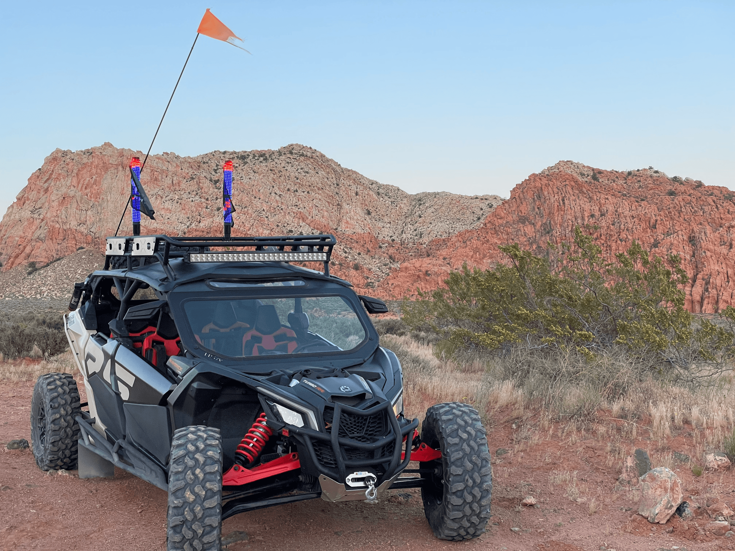 Off-road UTV parked on desert trail with red rock backdrop