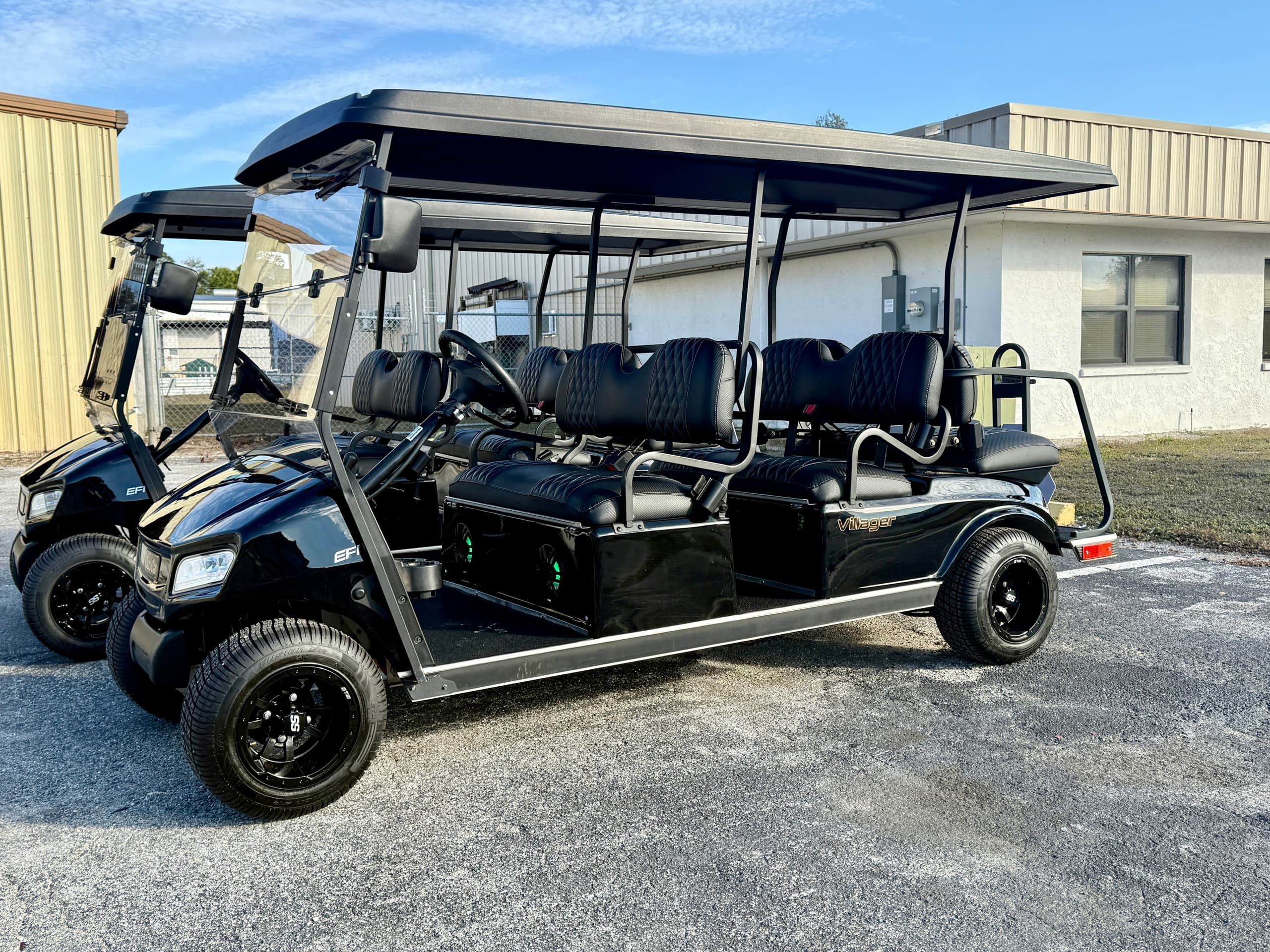 Black extended golf cart parked on pavement by rental shop building