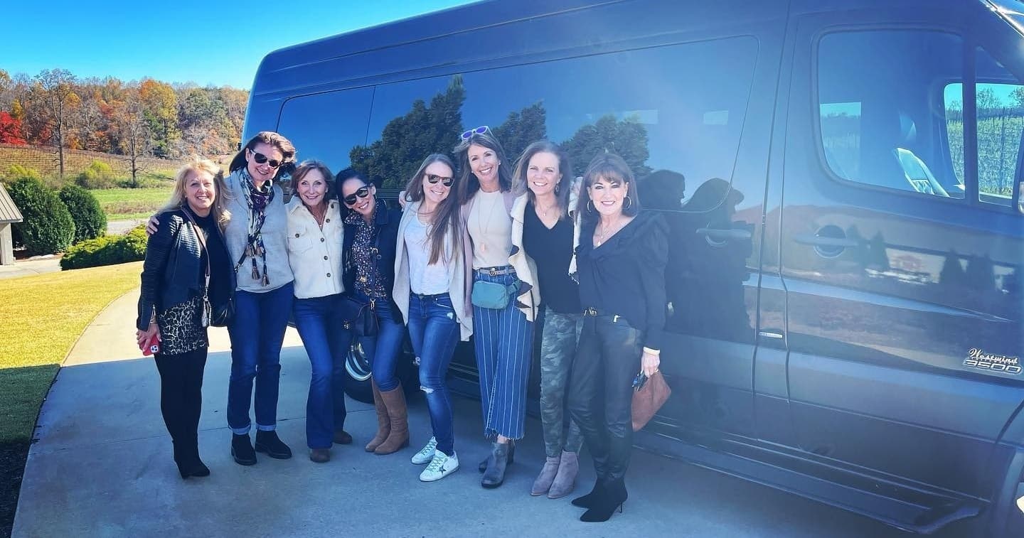 Group of friends smiling by shuttle van in sunny countryside