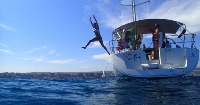 Sailors jumping from stern into clear blue Mediterranean sea