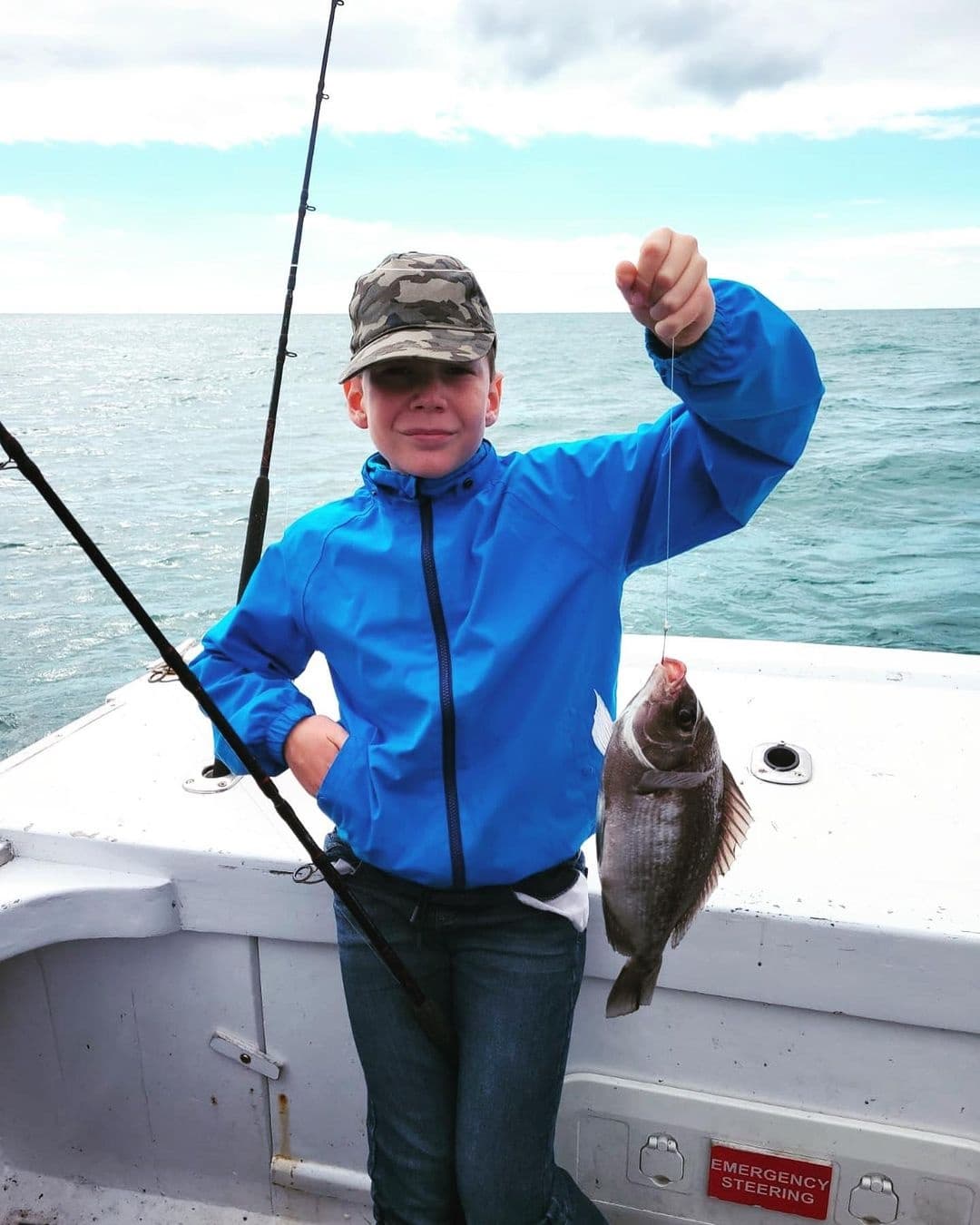 Young angler holding caught fish on charter boat off coast