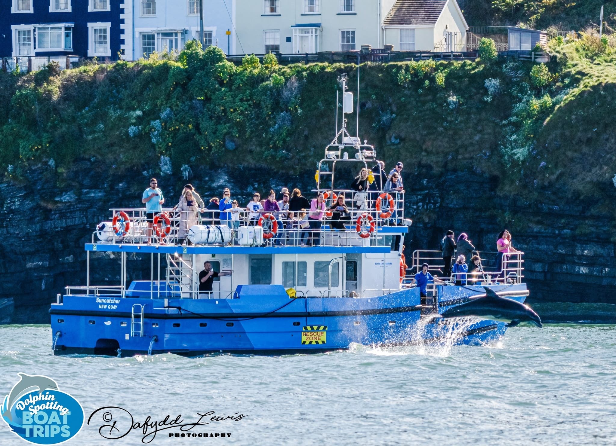 Crowded sightseeing boat cruising past cliffs on Newquay coast