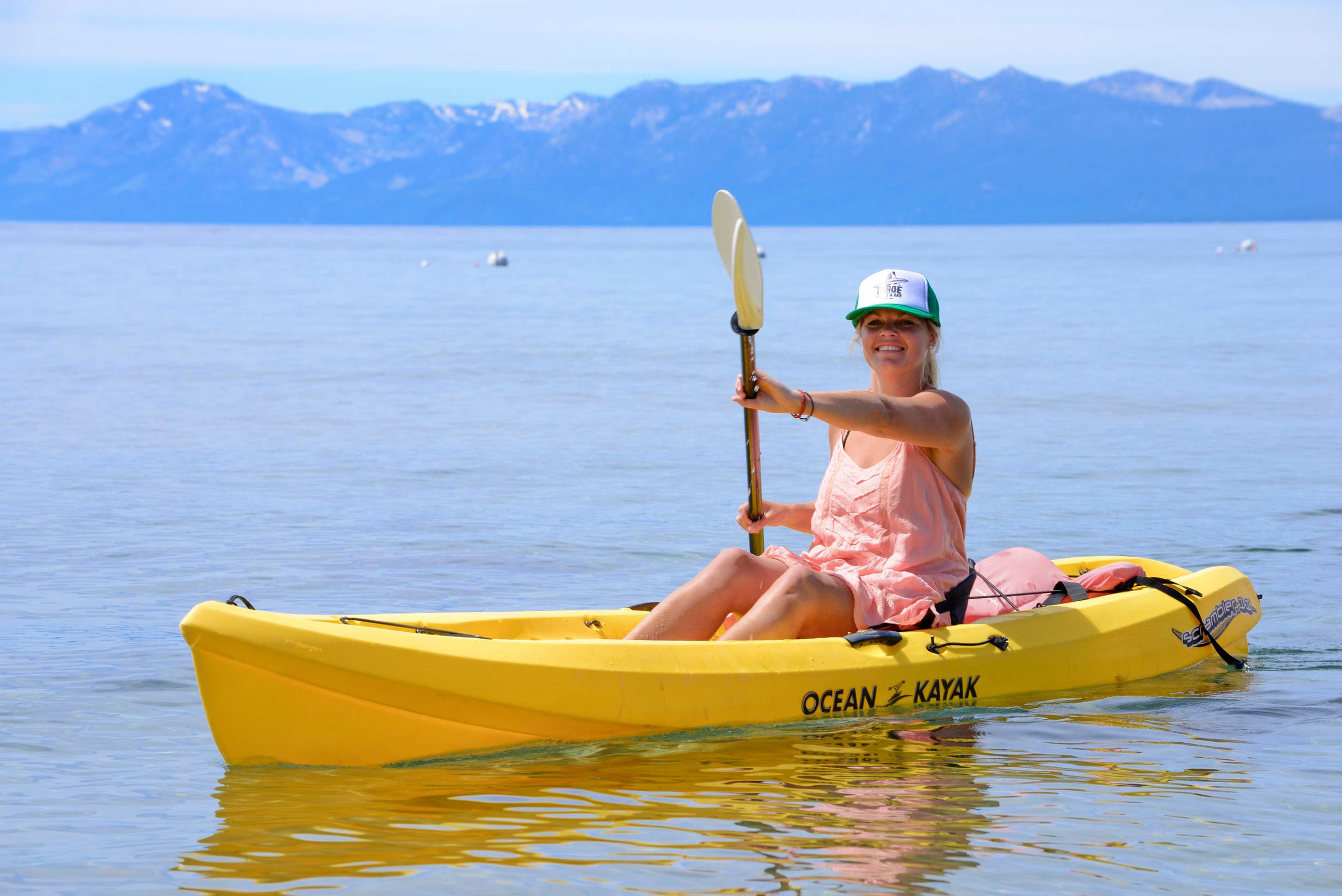 Solo kayaker paddling near open lake with mountain backdrop