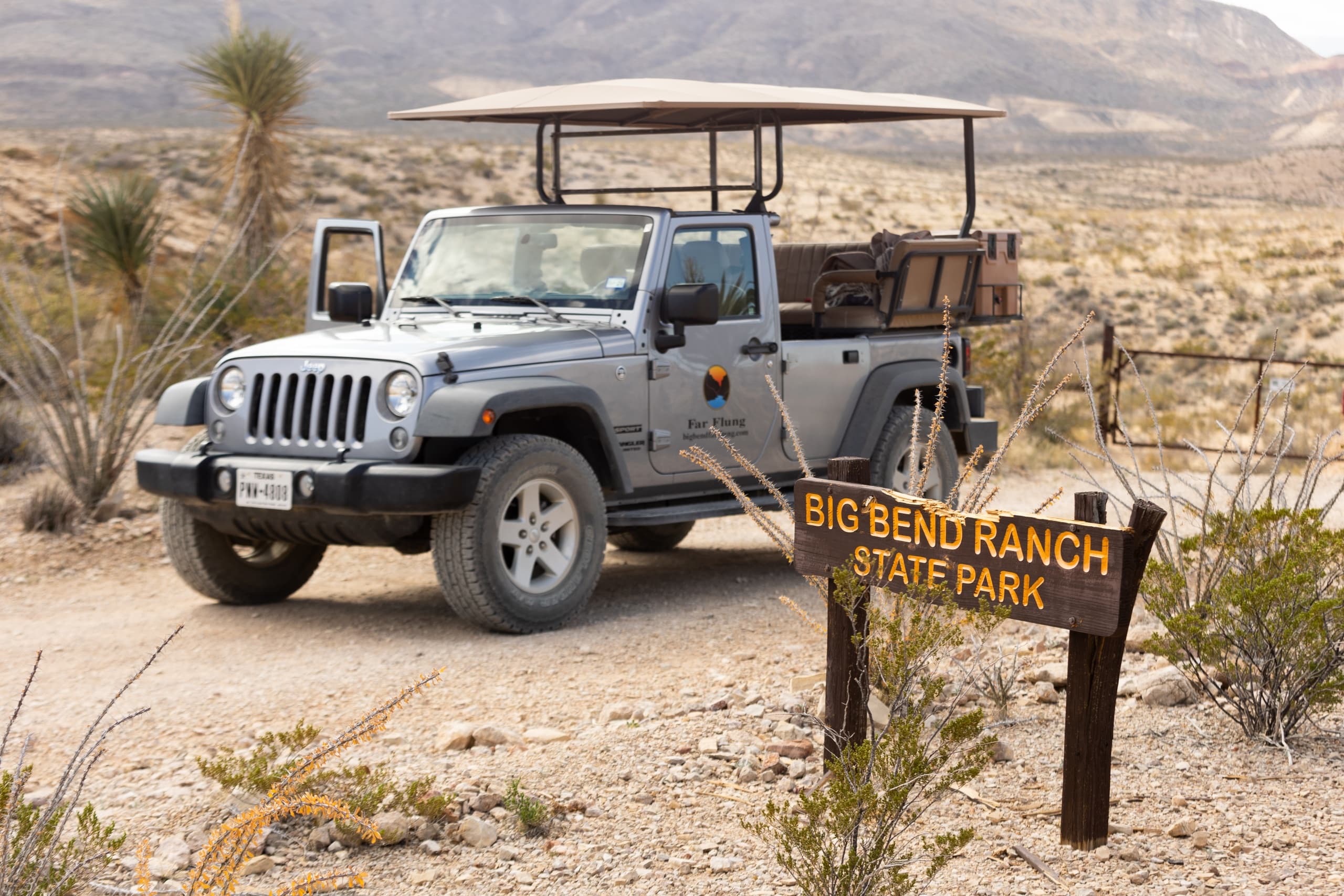 Open-top Jeep parked near Big Bend Ranch sign in desert