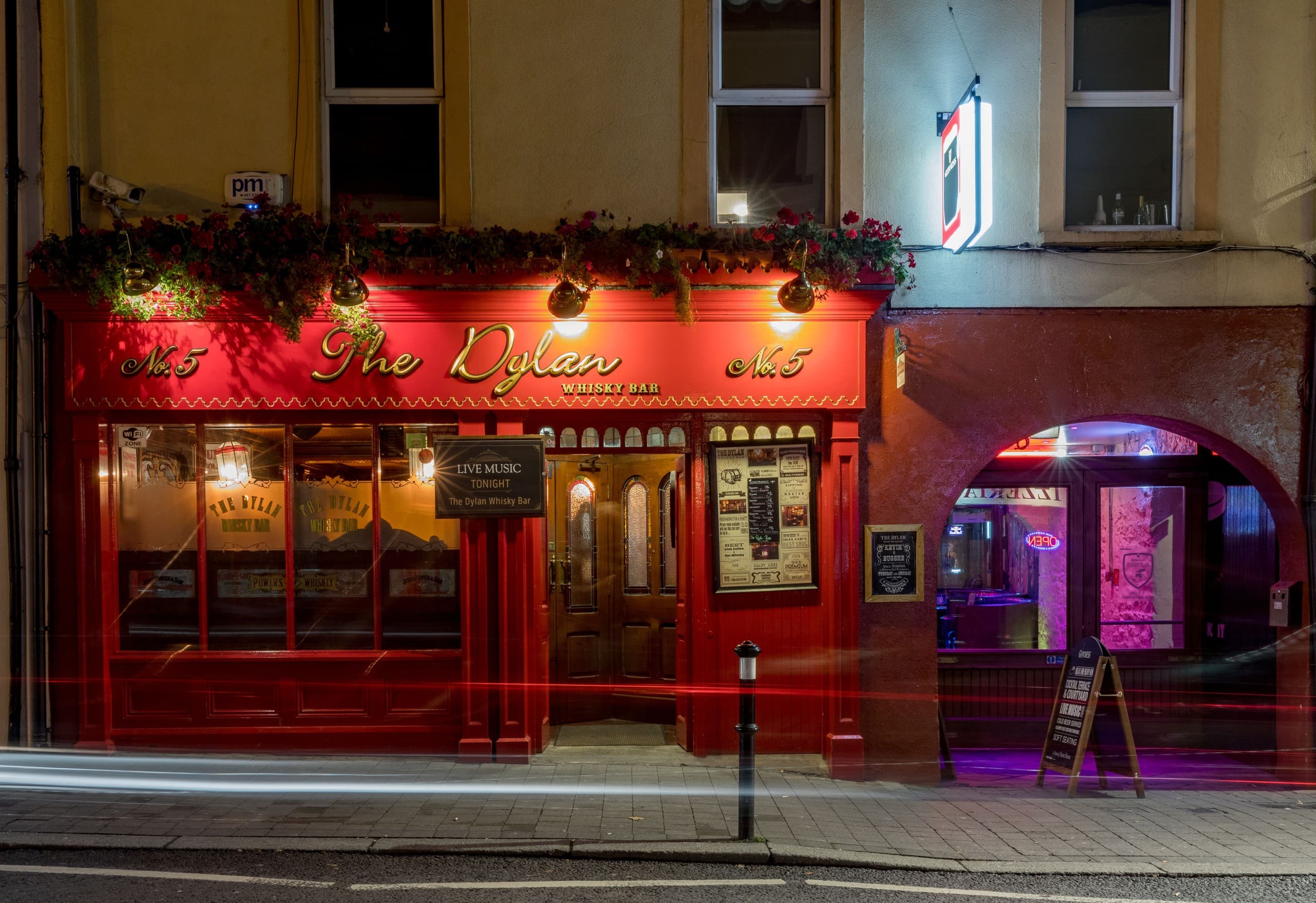 Red-painted pub exterior lit at night on urban street frontage