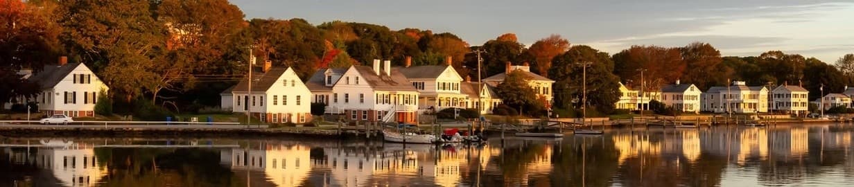 Autumn waterfront village reflected in calm bay at golden hour