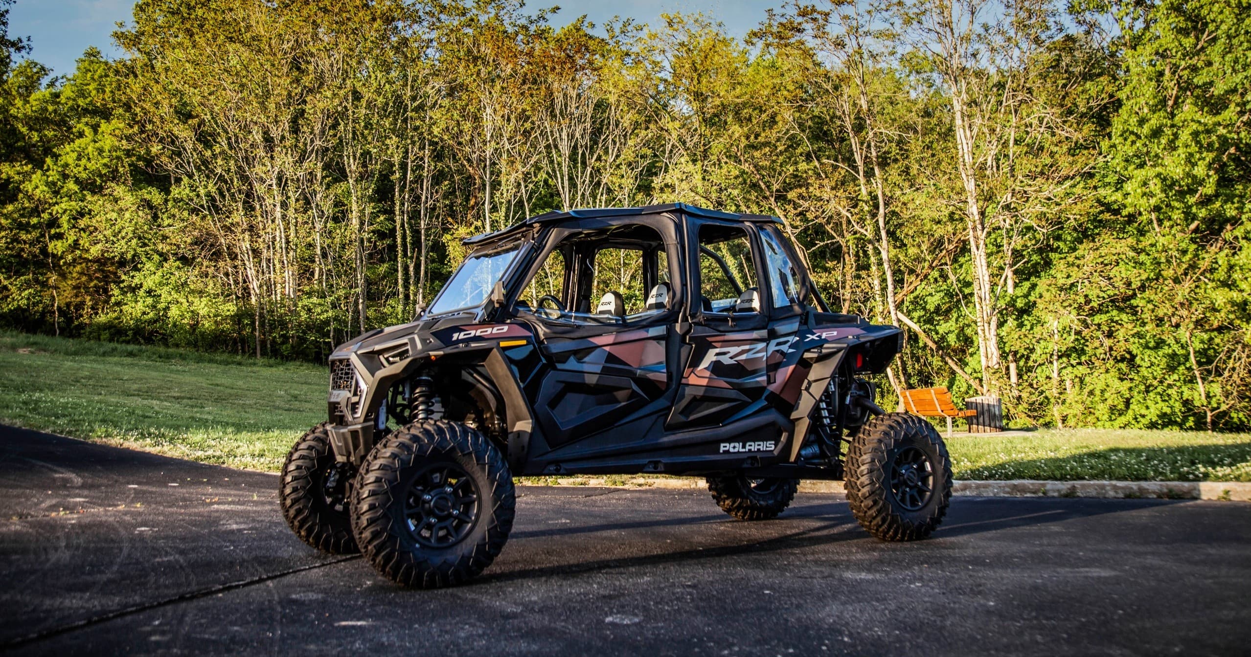 Off-road UTV parked on country road with forested sunset