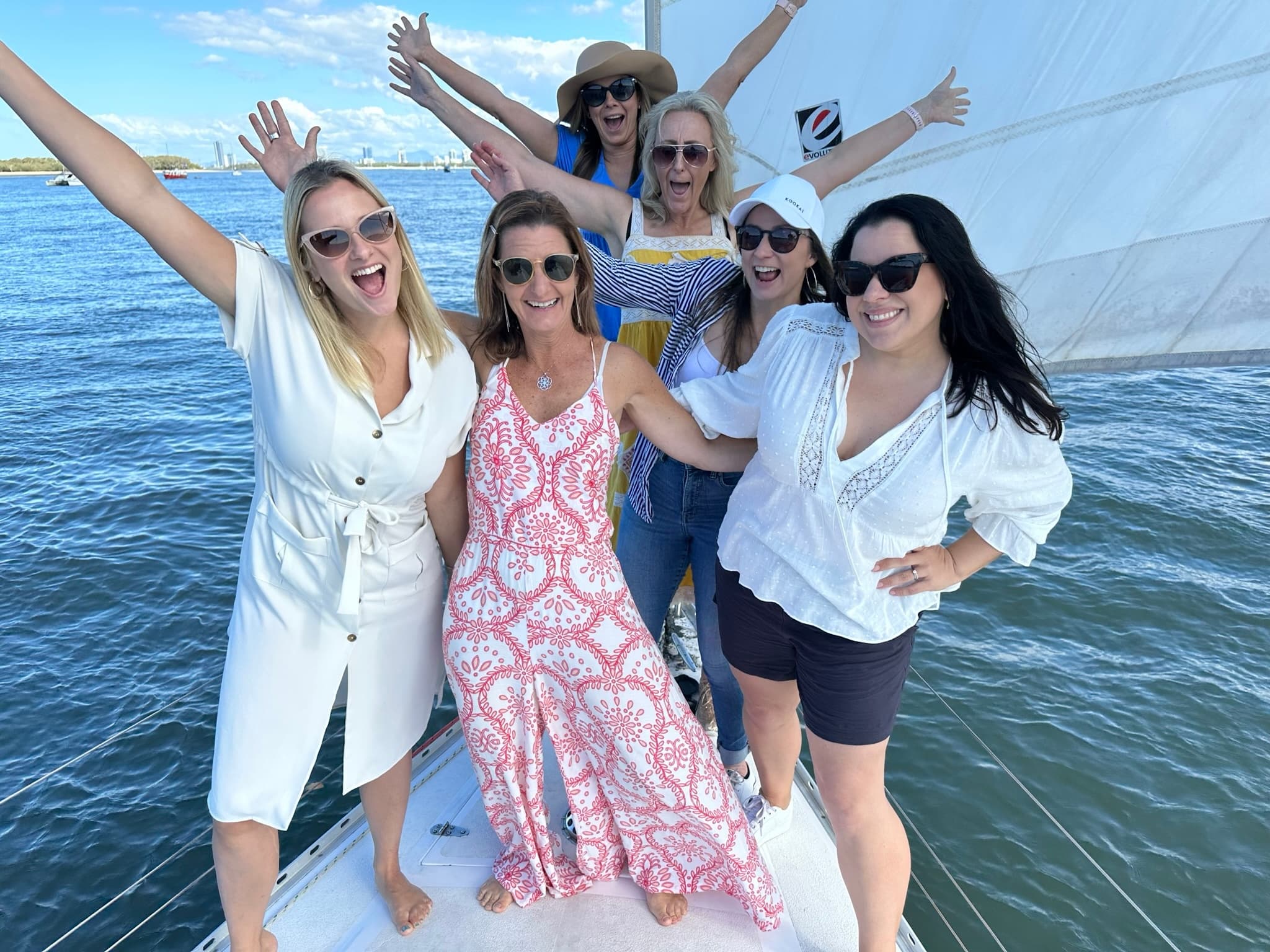 Group of friends on sailboat bow celebrating in sunny waters