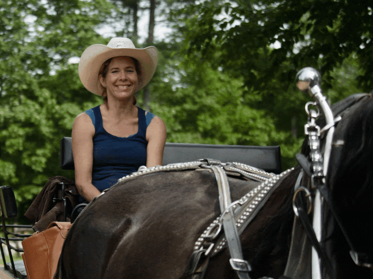 Group horseback riders trotting along shaded forest trail at ranch