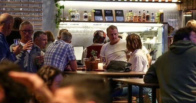 Crowded taproom scene with patrons socializing and drinking beer