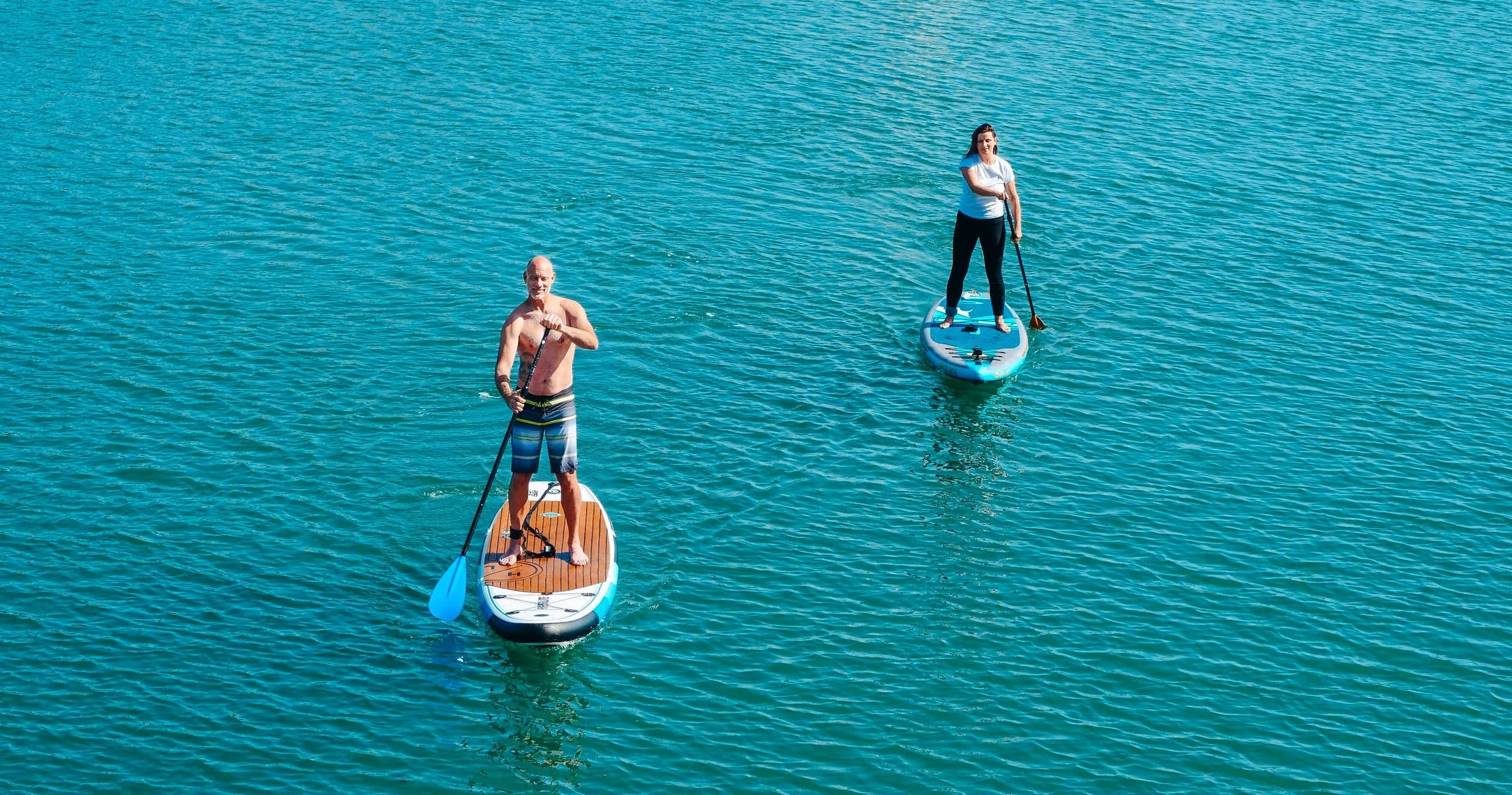 Two paddleboarders cruising clear turquoise coastal waters