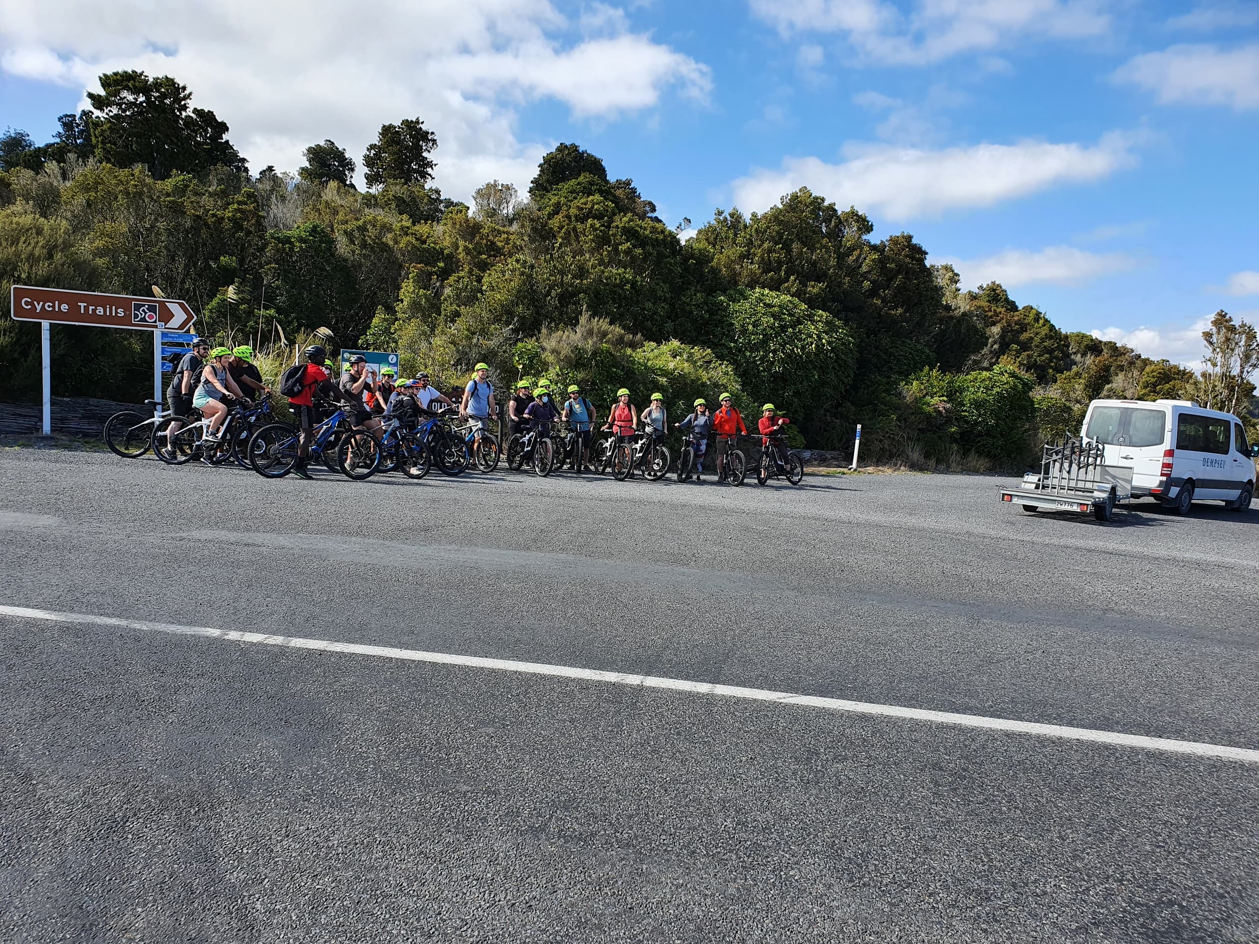 Guided road cyclists gathered roadside with support van and gear