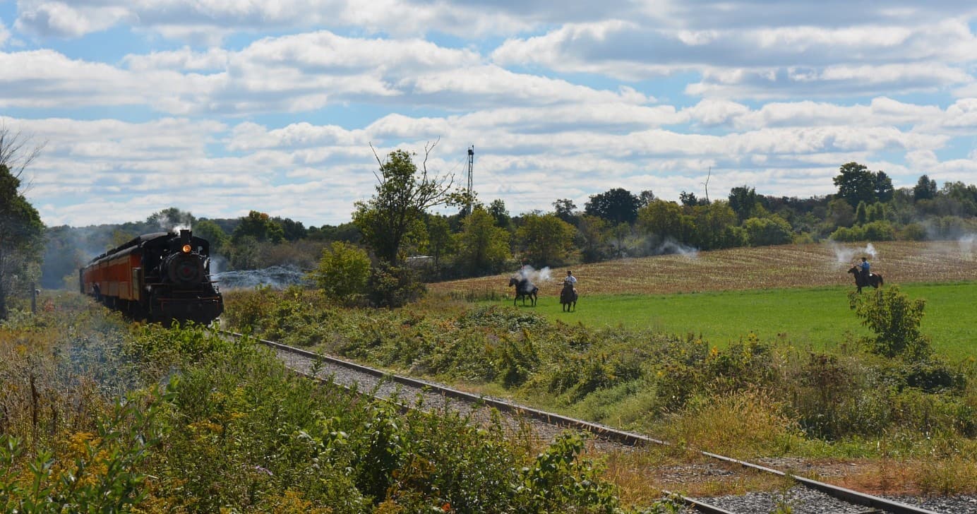 Scenic heritage train traveling rural fields with passengers