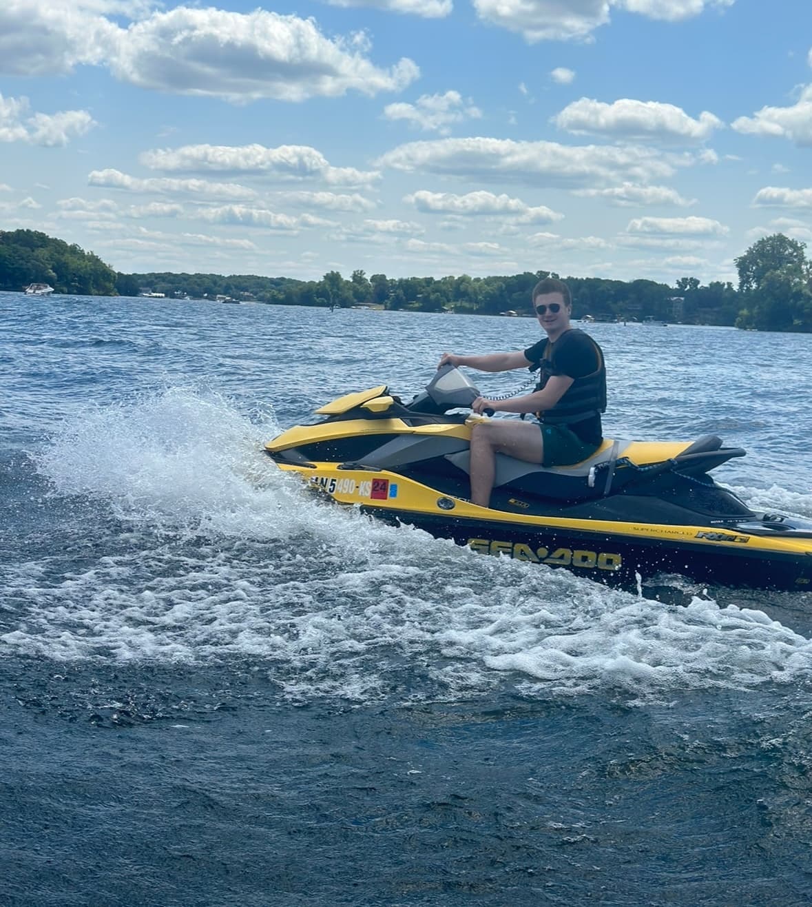 Rider on yellow jet ski speeding across a sunny lake, summer watersport