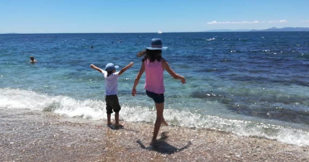 Children running on pebble beach along the Aegean Sea coastline