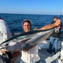 Fisherman holding large tuna on deck during deep sea fishing trip