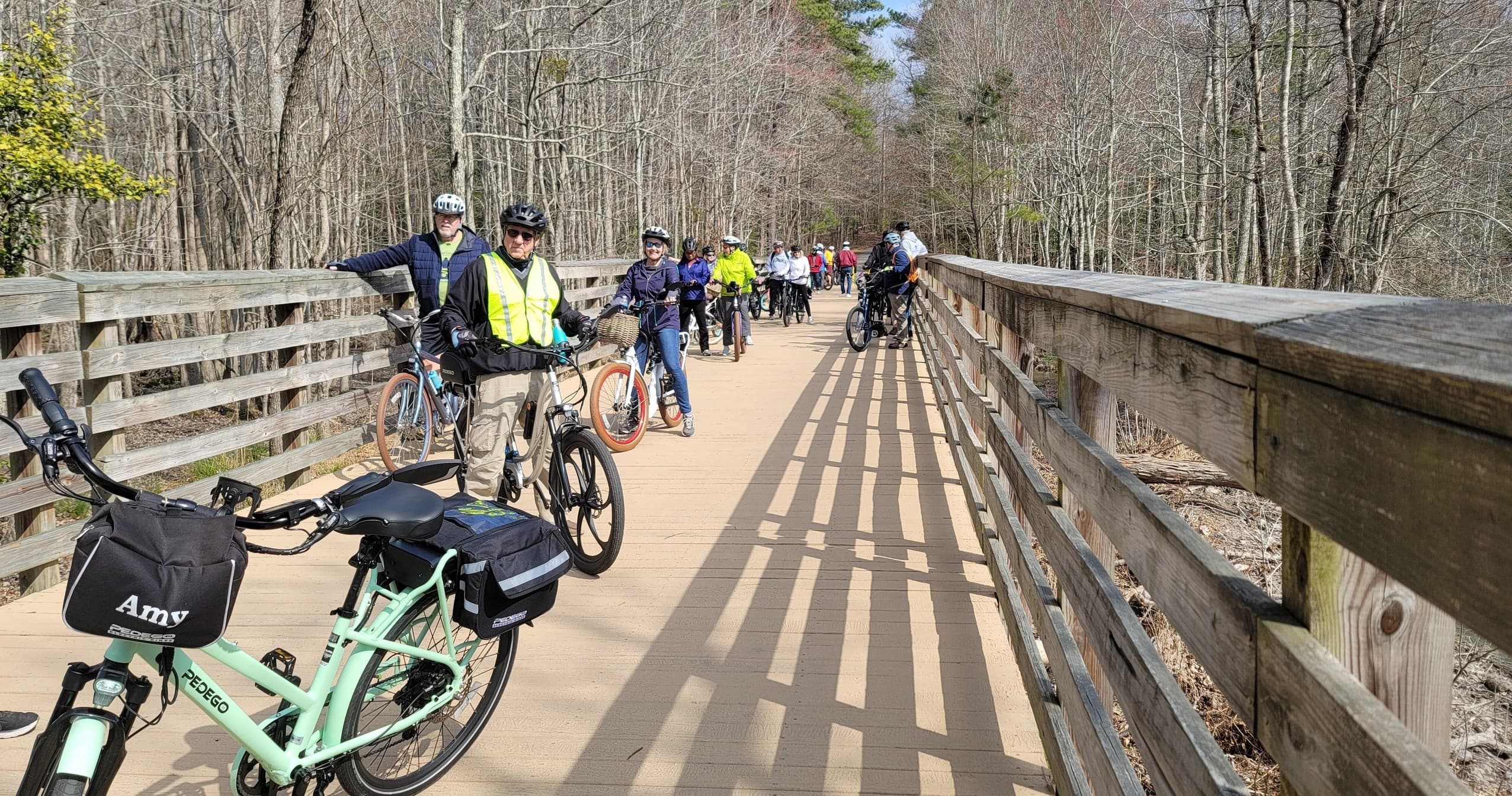 Group electric bike riders on scenic wooded boardwalk trail