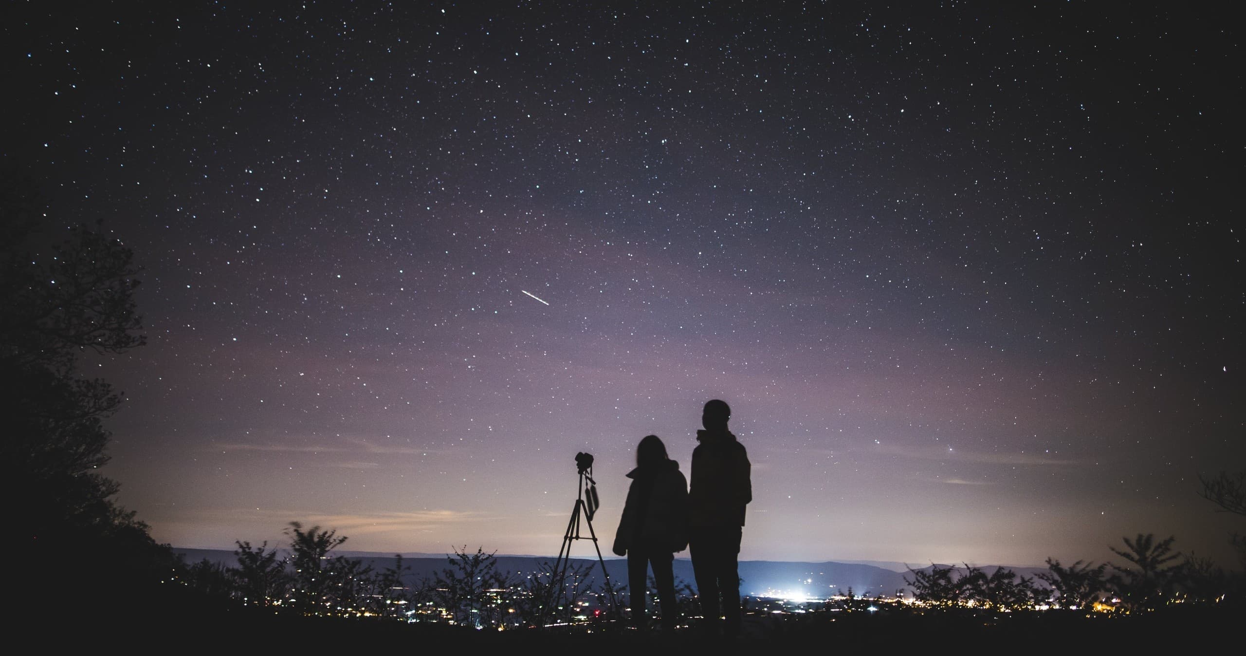 Stargazers silhouetted with tripod under Hawaiian night sky