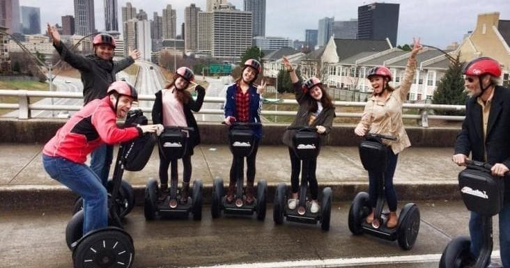Segway tour group posing on riverside promenade with city skyline