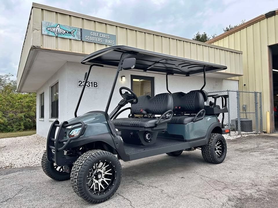 Dark gray lifted golf cart parked outside rental shop on concrete pad